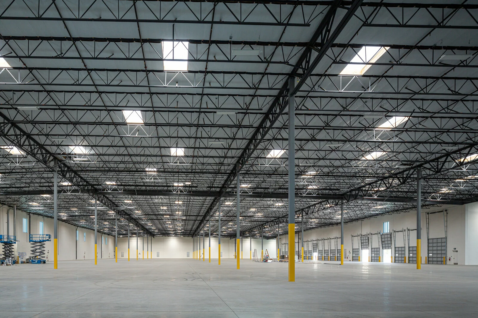 Almond Avenue, large interior facility, garage doors, gray and yellow beams, skylight windows.