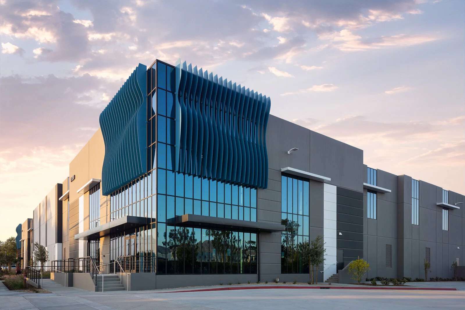 Exterior Almond Avenue facility, contemporary blue wave design on glass exterior, photo taken at sunset.