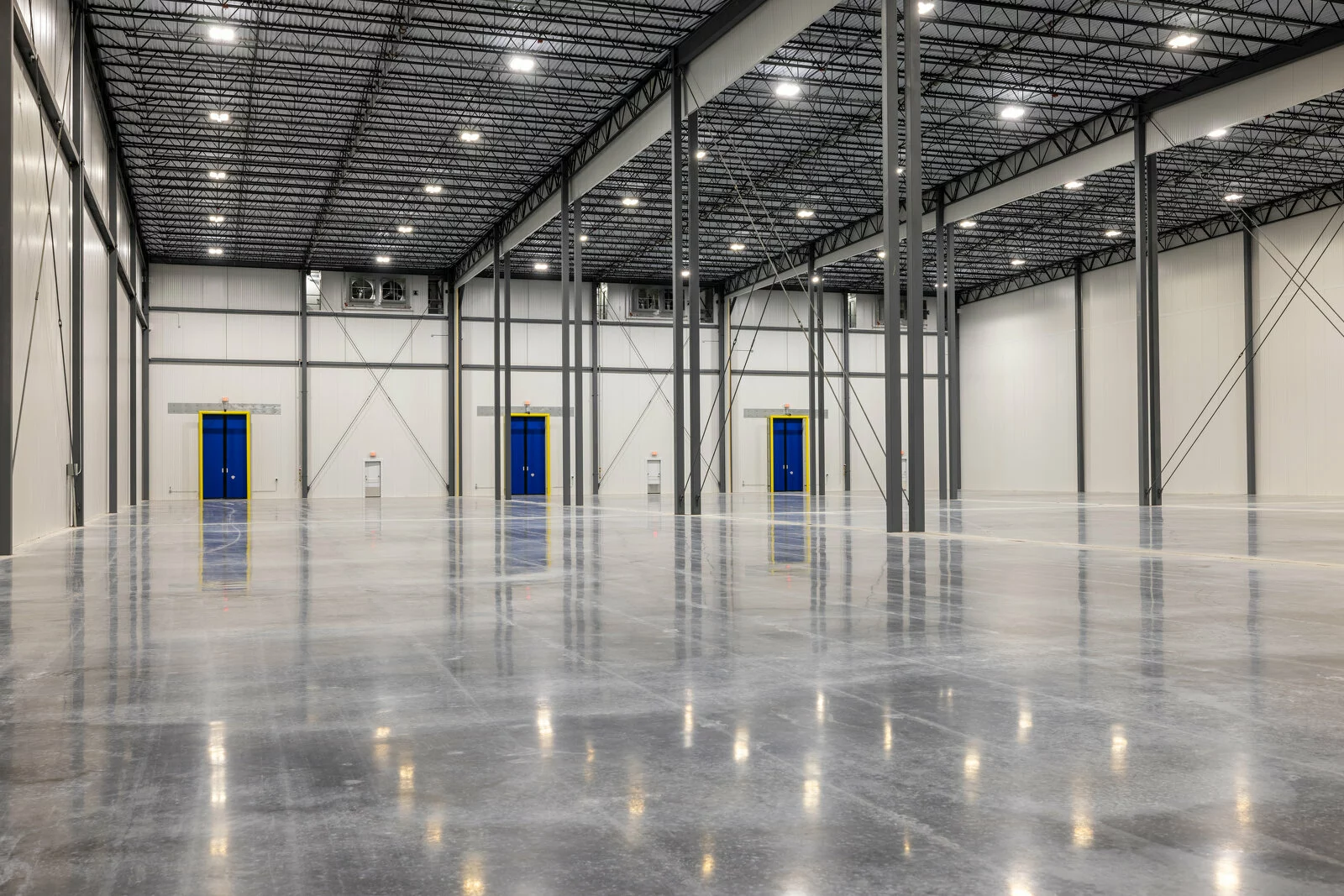 Cold Summit interior facility, 3 blue doors with yellow trim, gray beams, bright lights, tall ceilings.