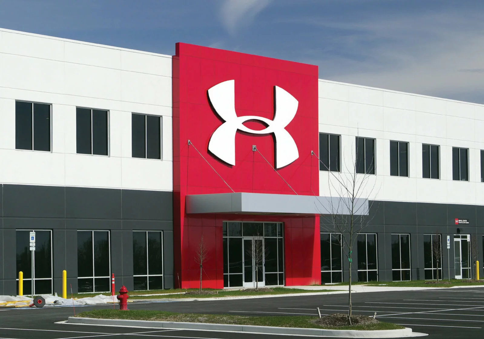 under armour front entrance. large red facade with large under armour signage, parking lot in front.
