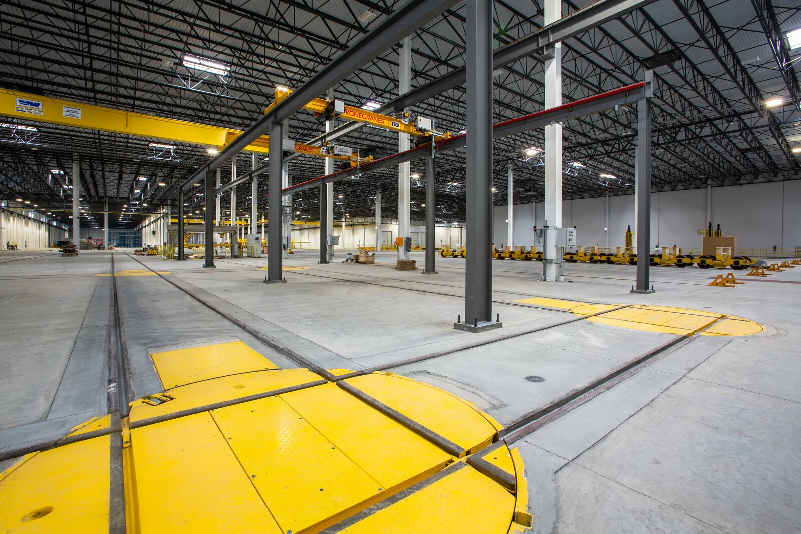 Interior Warehouse/Manufacturing Facility, yellow safety zones, vast warehouse, high ceilings, load bearing beams.
