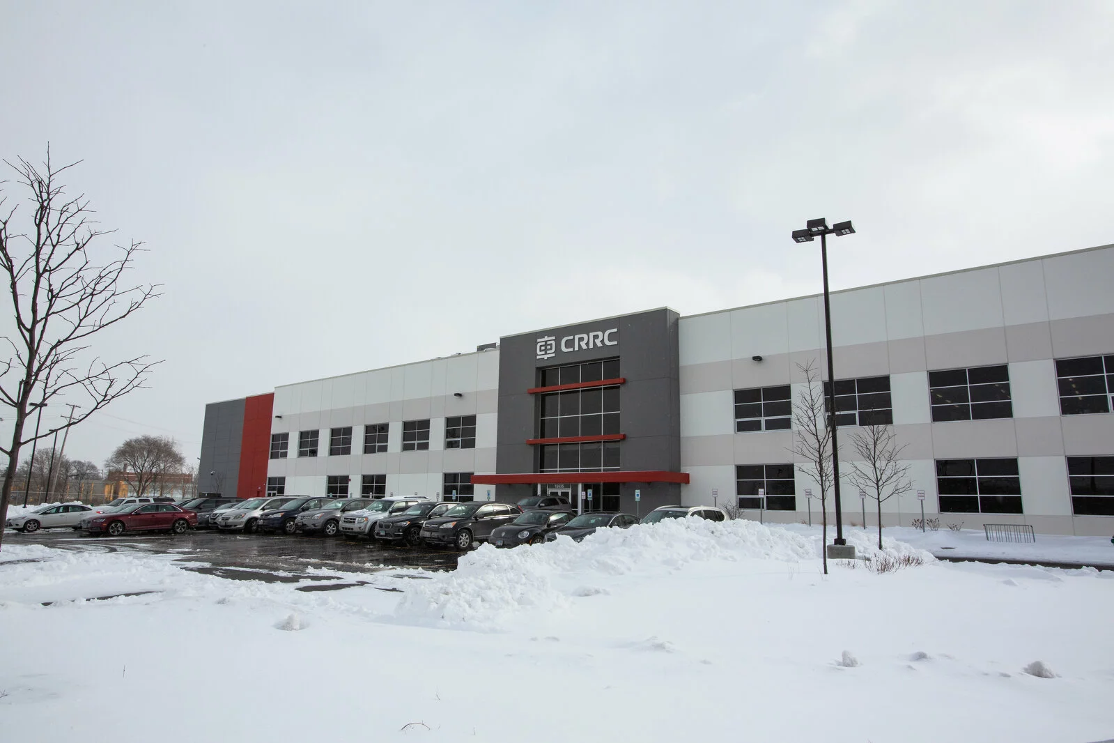 Exterior Building, gray and white building with red trim, parking lot in front of building, photo taken on a snowy day.