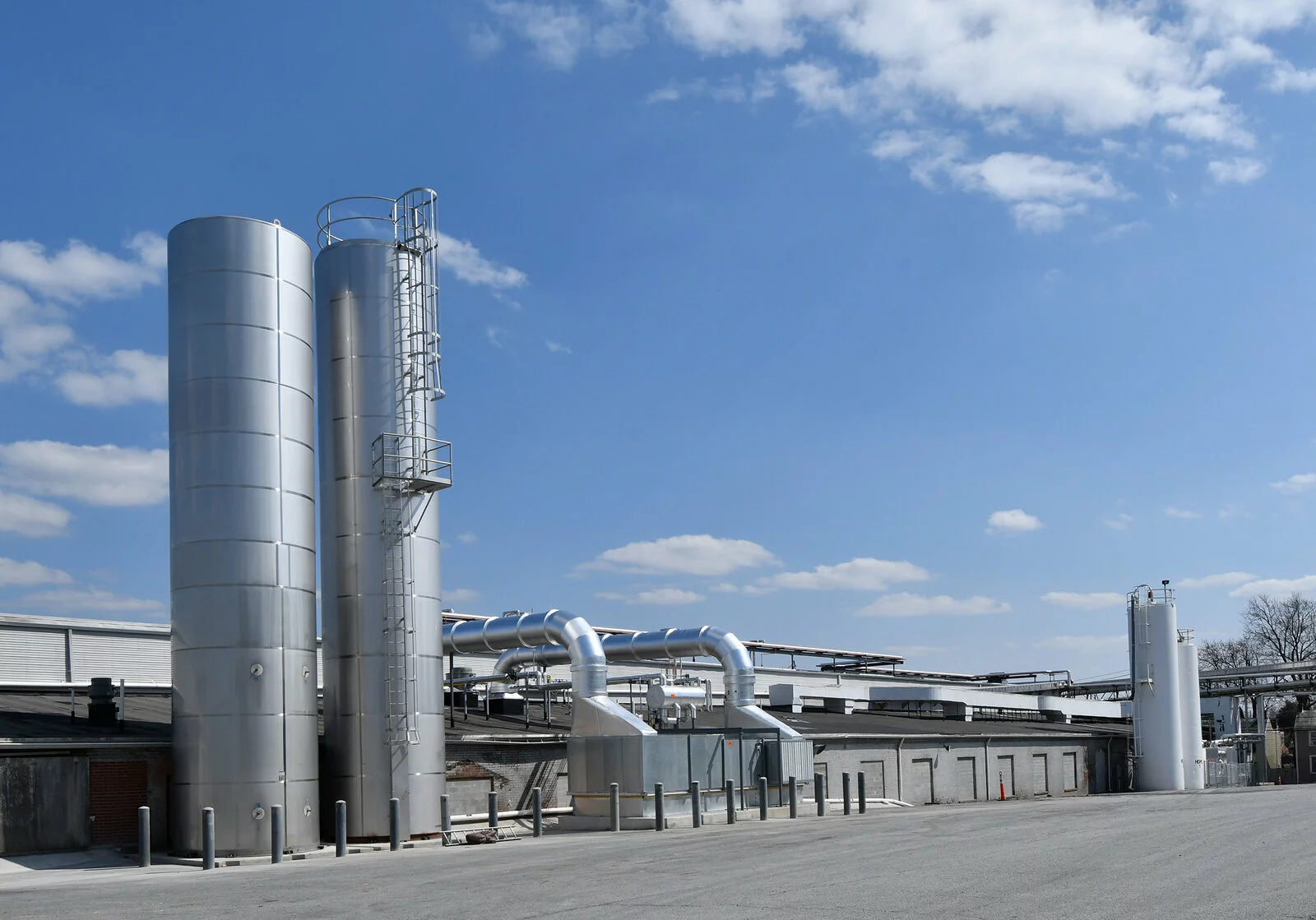 Exterior building multiple silver silos, photo taken on a sunny day with clouds