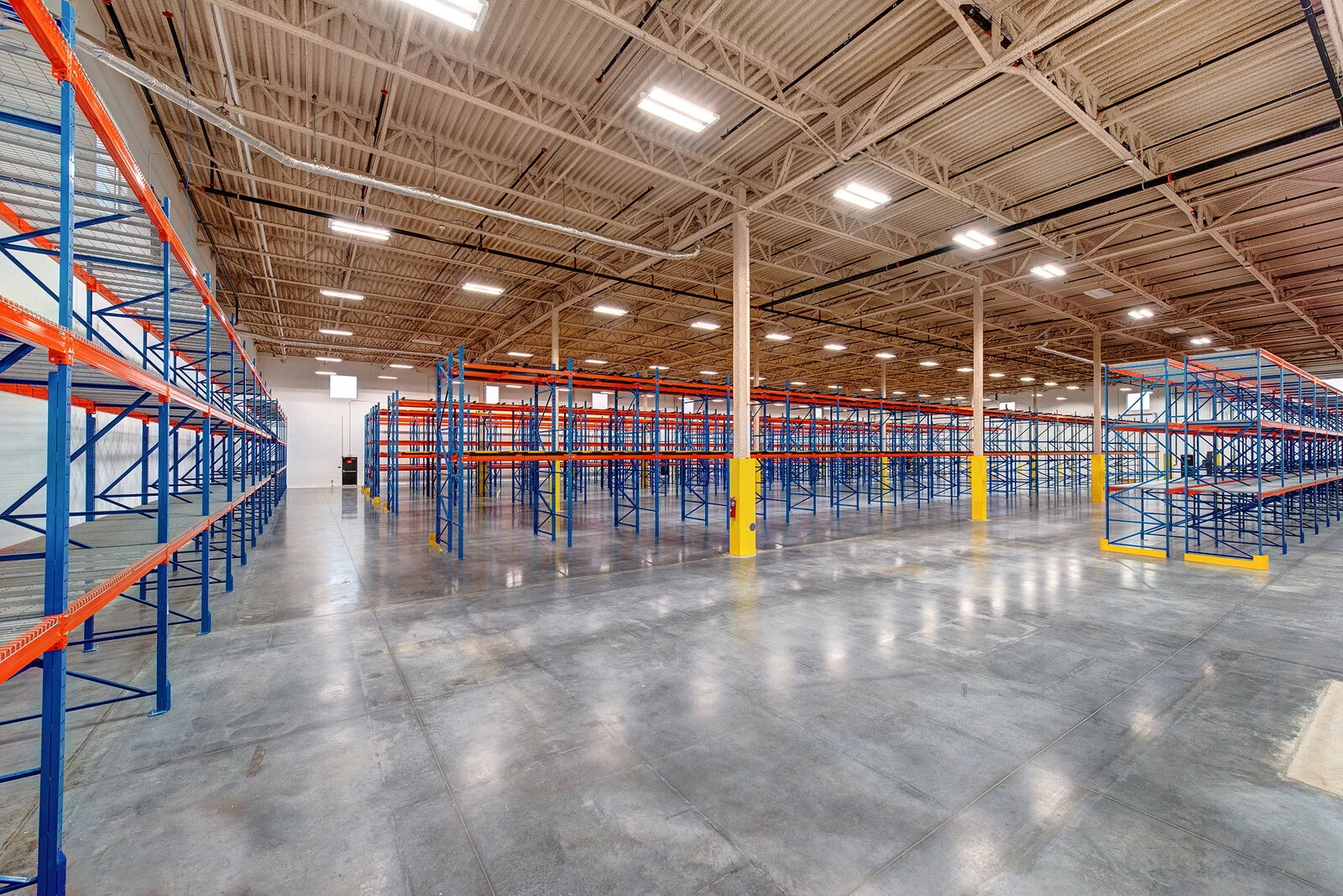 Interior Warehouse building, concrete floor, vast space, many rows of industrial shelving.