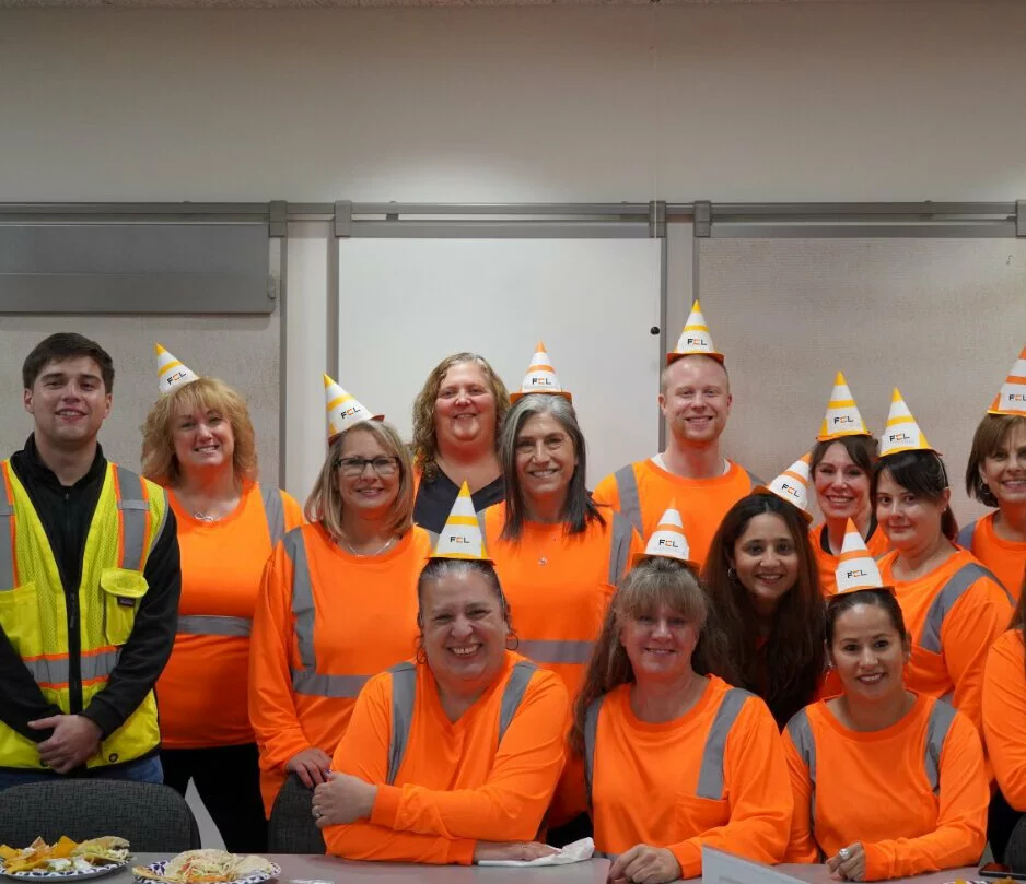 employees smiling wearing orange shirts and FCL party hats