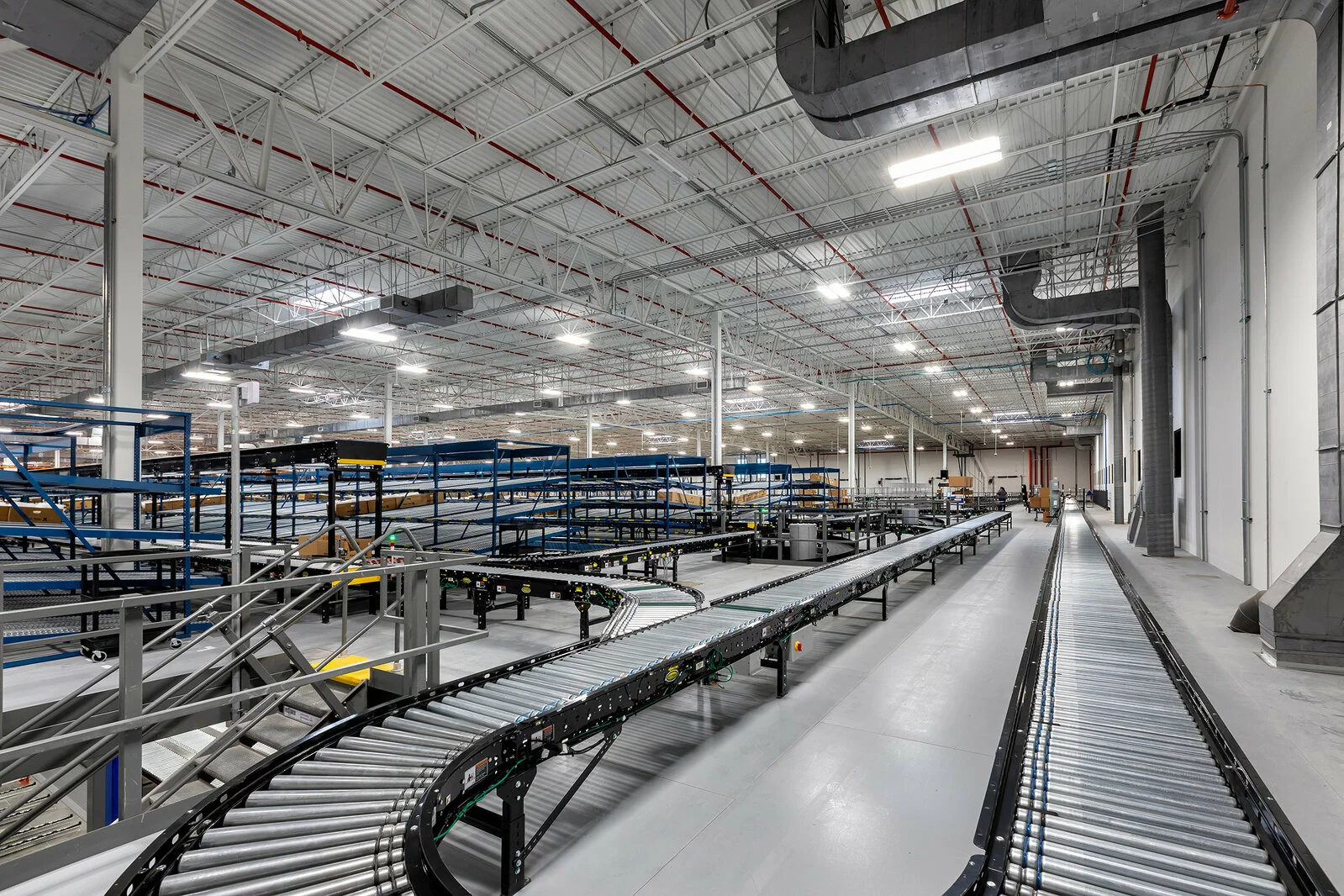 Interior Warehouse/ Distribution center with conveyor belts, vast interior space, multiple rose of shelving.