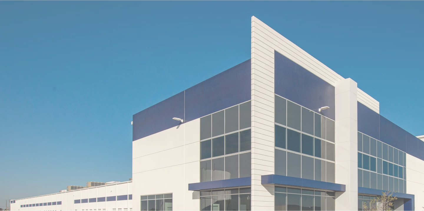 Exterior Photo of Cold Storage Facility, Contemporary white building with blue trim, photo taken on a sunny day.