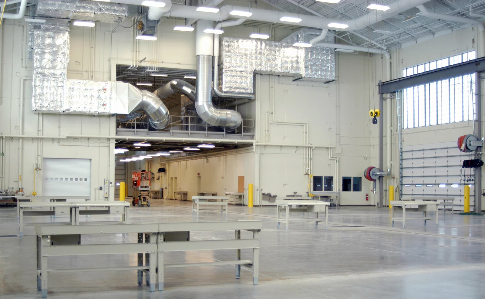 Interior US Army T.E.M.F facility, workbenches throughout facility, large ventilation chambers, large garage doors, concrete floor, high ceilings.