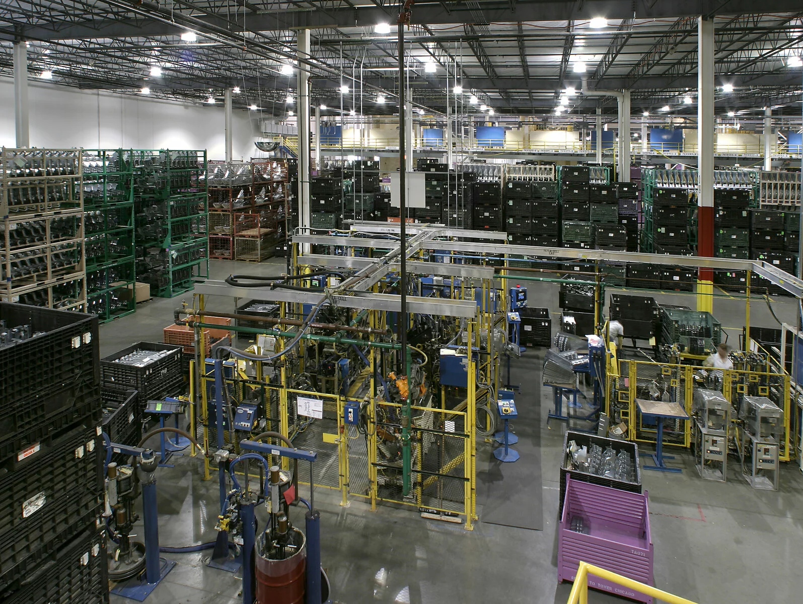 interior manufacturing warehouse, countless rows of crates on shelves, support columns throughout the building.