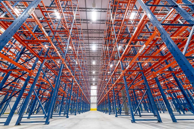 Empty blue and orange racks are lined up in several rows in a cold storage facility.